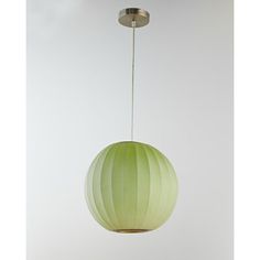 a green ball hanging from a ceiling light with a white wall in the back ground