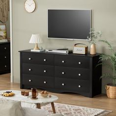 a flat screen tv mounted to the side of a black dresser in a living room