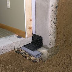 the corner of a house that is under construction, with some rocks and gravel on the ground