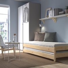 a room with a bed, table and chair in it next to a book shelf