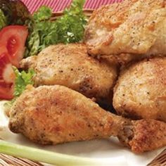 some chicken is sitting on a plate with lettuce and tomatoes in the background