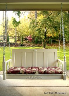 a white porch swing with pillows on it