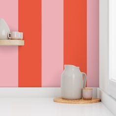 a pink and orange striped wall in a kitchen with white counter top, wooden shelf and vase