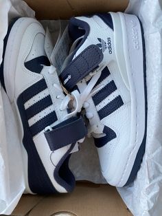 a pair of white and blue adidas sneakers in a box with the shoe laces down