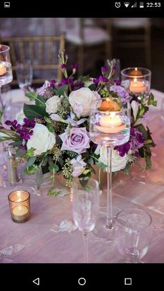 an arrangement of flowers and candles on a table