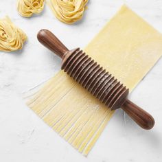 the pasta is being made with a wooden spatula on top of some uncooked noodles