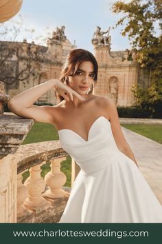 a woman in a white wedding dress leaning on a wall with her hand on her head