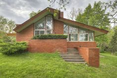 a red brick house sitting on top of a lush green field