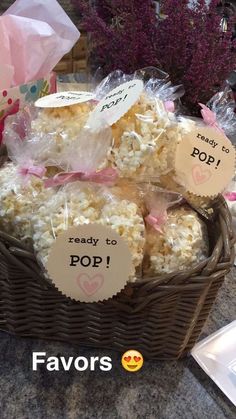 a basket filled with lots of popcorn sitting on top of a table next to flowers