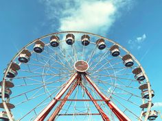 a ferris wheel with several lights on it's side and blue sky in the background