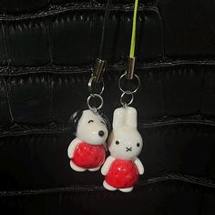 two key chains are attached to the back of a black leather bag with a white rabbit holding a red heart