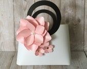 a pink flower sitting on top of a white tabletop next to a pair of black hair ties