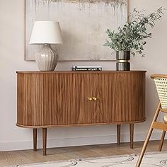 a wooden cabinet sitting next to a chair in a room with a painting on the wall