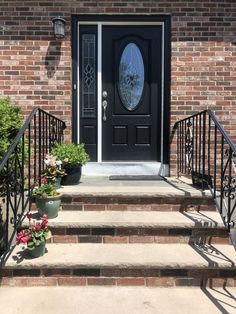 a black front door with two potted plants on the steps