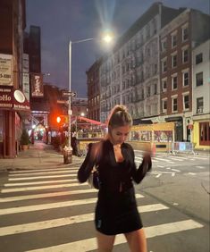 a woman walking across a street at night