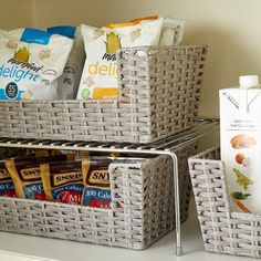 two wicker baskets filled with food on top of a kitchen counter next to a bottle of milk