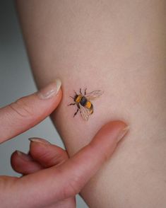 a woman's arm with a small tattoo of a bee on it