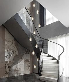 a spiral staircase with lights hanging from the ceiling and marble flooring in front of it