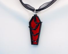 Spooky Season is almost here, and this is a perfect accessory. This coffin-shaped pendant has a blood-red mirror backing on a 3d printed coffin with Bats. The pendant measures 2 inches and is strung on a faux leather cord measuring 18 inches, 2 inches. Weird Jewelry, Red Mirror, Blood Red, Black Mirror, Spooky Season, Red And Black, Leather Cord, 3d Printed, Pendant Necklaces