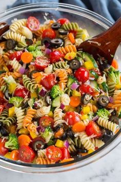 a colorful pasta salad with tomatoes, broccoli, olives and other vegetables