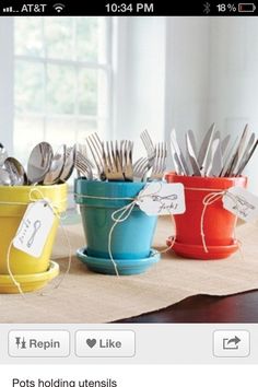 four pots with forks and spoons in them sitting on a table next to each other