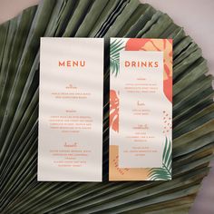 two menus sitting on top of a palm leaf