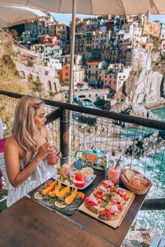 a woman sitting at a table with food and drinks