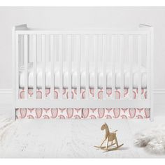 a white crib with a rocking horse next to it and a rug on the floor