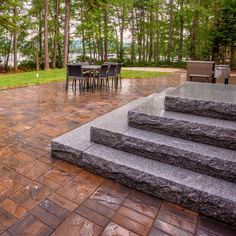 an outdoor patio with steps leading up to a table and chairs on the other side