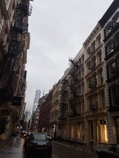 cars are parked on the street in front of tall buildings with balconies and fire escapes