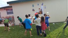 a group of children standing in front of a house with balloons on the back of their heads