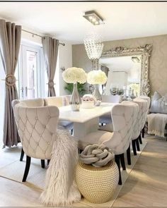 a dining room table with white chairs and chandelier