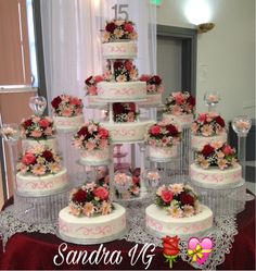 a wedding cake with pink and red flowers on the top is surrounded by other cakes