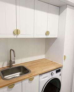 a washer and dryer in a small room with white cupboards on the wall