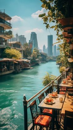 an outdoor dining area with tables and chairs next to the river in front of tall buildings