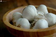 a wooden bowl filled with white garlic on top of a table