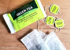 a bag of green tea sitting on top of a wooden table next to some tags