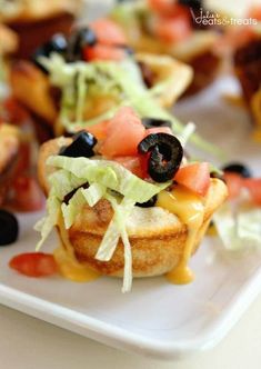 small appetizers with lettuce, tomatoes and olives on them are ready to be eaten