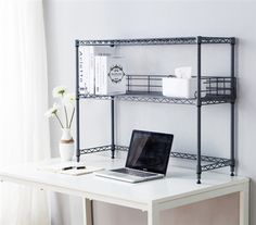 a laptop computer sitting on top of a white desk next to a shelf with shelves