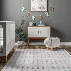 a baby's room with grey walls and white furniture