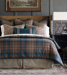 a bed with plaid comforter and pillows in a bedroom next to a painting on the wall