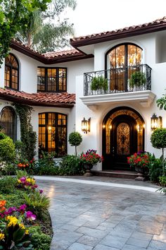 a large white house with lots of windows and plants in the front garden area,