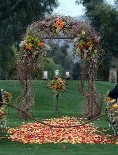 an outdoor ceremony setup with flowers and foliage on the ground, in front of trees