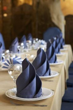 the table is set with blue napkins and wine glasses