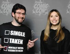 a man and woman standing next to each other in front of a gray wall with the words single taken on it