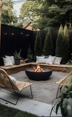 an outdoor fire pit surrounded by wooden chairs and pillows in the middle of a backyard