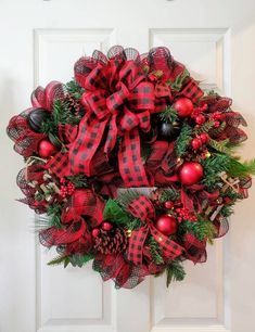 a red and black christmas wreath hanging on a door