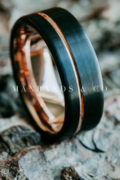 a wedding band with two tone gold and black inlays on top of a rock