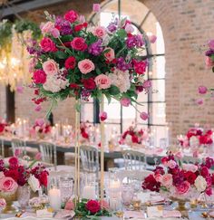 a tall vase filled with lots of pink and red flowers on top of a table