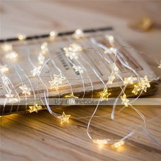 a wooden table topped with a book covered in white stars and string lights on top of it